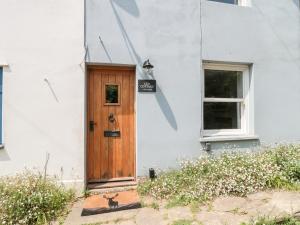 a white house with a wooden door at Lea Cottage in Bridport