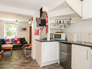 a kitchen with white cabinets and a living room at Lea Cottage in Bridport