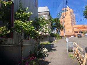 a sidewalk next to a building with trees and flowers at art.paradigm in Kushiro