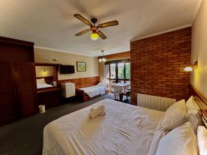 Habitación de hotel con cama y ventilador de techo. en Natur Hotel, en Gramado