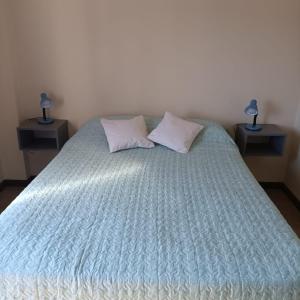 1 cama con edredón azul y 2 mesitas de noche en Departamento Centrico San Martin en San Salvador de Jujuy