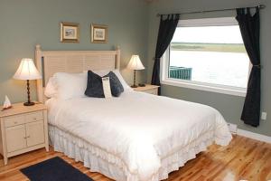 a bedroom with a white bed and a window at Auberge Bay Wind Suites in Chéticamp
