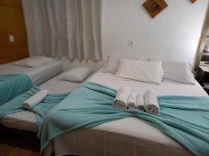 a bed with two towels and two pillows on it at Estalagem Brumone in Monte Verde