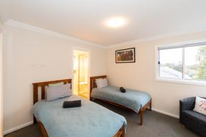 a bedroom with two beds and a couch and a window at Armidale Cottage - House 1 in Armidale