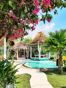 a resort swimming pool with a gazebo and pink flowers at Janur Bungalow in Borobudur