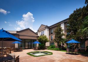 a courtyard with tables and umbrellas in front of a building at Holiday Inn Express and Suites New Orleans Airport, an IHG Hotel in Saint Rose