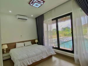 a bedroom with a bed and a large window at Eagle Bavi Resort in Ba Vì