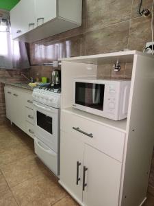 a white kitchen with a microwave and a stove at Complejo M&M in Bialet Massé