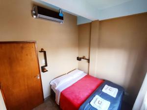 Habitación pequeña con cama con manta roja en Hotel AEROPUERTO Jujuy en Perico