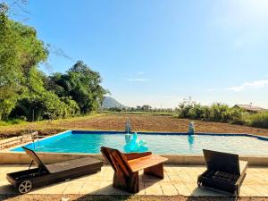 a swimming pool with two chairs and a table next to it at Rumah Kurnia in Kangar