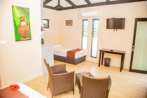 Seatiki Resort Fiji On Coast في Sigatoka: غرفة فندقية بسرير وطاولة وكراسي