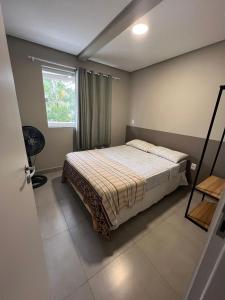 a bedroom with a bed and a window at Residencial Tia Dilma in Bombinhas