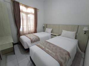 two beds in a hotel room with a window at HASTOSTAY @suryodiningratan in Timuran