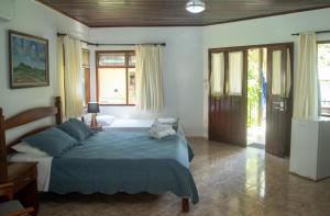 een slaapkamer met een bed met een blauw dekbed bij Pousada Casa Rosa in Alto Paraíso de Goiás