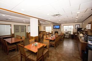 a dining room with tables and chairs and a television at Service Plus Inns & Suites Drayton Valley in Drayton Valley