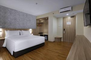 a bedroom with a white bed and a television at ASTON Nagoya City Hotel in Batam Center