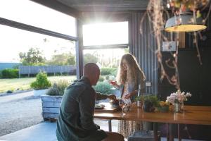 a man and woman sitting at a table with a glass of wine at Inverloch Glamping in Inverloch