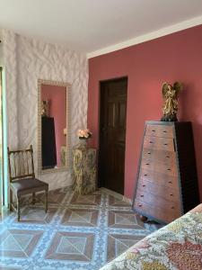 ein Schlafzimmer mit rosa Wänden, einer Kommode und einem Stuhl in der Unterkunft Mansão Dubai in Santa Cruz Cabrália