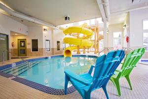 einen Pool mit Rutsche und zwei blauen Stühlen in der Unterkunft Service Plus Inns & Suites Drayton Valley in Drayton Valley