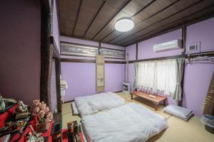 een slaapkamer met paarse muren en een bed en een tafel bij 小樽民泊太田1号館 in Otaru