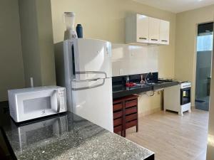 a kitchen with a white refrigerator and a microwave at Casa 4 - Vila Francisco in Pirenópolis