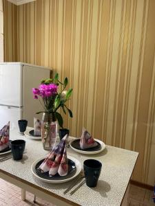 une table avec des assiettes de nourriture et un vase de fleurs dans l'établissement Аэропорт Астана 5 минут юг1, à Astana