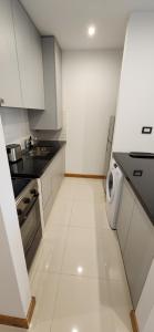 Una cocina con gabinetes blancos y lavavajillas. en Departamento Temporario 54, en La Plata