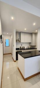 Una cocina con gabinetes blancos y una encimera negra. en Departamento Temporario 54, en La Plata