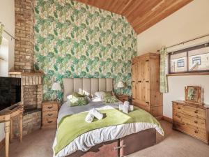 Un dormitorio con una cama con una pared verde estampada en The Granary - Uk36673, en Goulsby