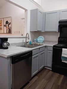 a kitchen with white cabinets and a black dishwasher at Tara condo in San Antonio
