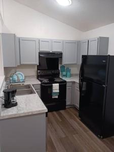 uma cozinha com um frigorífico preto e armários brancos em Tara condo em San Antonio