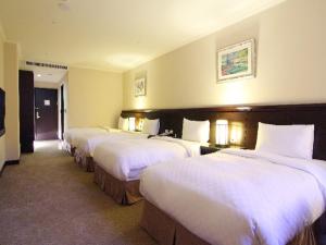 a row of four beds in a hotel room at Chong Yu Hotel in Taoyuan