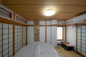 a bedroom with a bed and a table and windows at 小樽民泊太田2号館 in Otaru