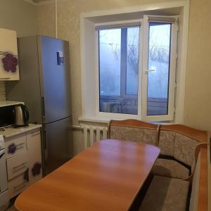 a kitchen with a wooden table and a refrigerator at Однокомнатная квартира в Караганде in Karagandy