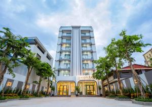 贡布The Square Kampot Hotel的一栋高大的白色建筑，前面有树