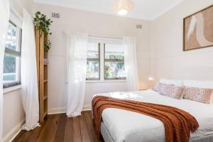 a white bedroom with a bed and two windows at Shirley Beach House, right in heart of Byron Bay, walking distance to town and most famous beaches in Byron Bay