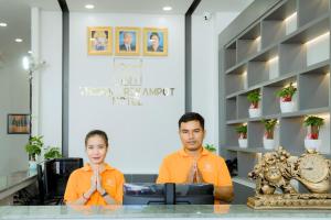 Um homem e uma mulher sentados à mesa com as mãos à frente. em The Square Kampot Hotel em Kampot