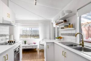 a white kitchen with white cabinets and a sink at Shirley Beach House, right in heart of Byron Bay, walking distance to town and most famous beaches in Byron Bay