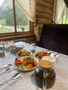 uma mesa com pratos de comida e um frasco sobre ela em Altyn Arashan guesthouse em Mineralʼnyy Istochnik Altyn-Arasan