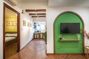 a room with a green wall with a television at Homestay Hang Tre 5min to Bar street in Hanoi