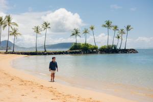 a man standing on a beach with palm trees at The Kahala Hotel and Resort in Honolulu