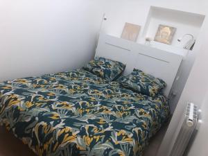 a small bedroom with a bed with a floral bedspread at Appartement paisible proche centre ville in Bron