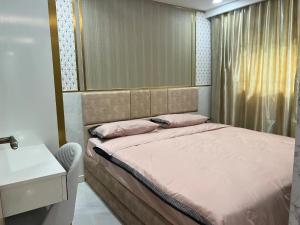 a bed with pink pillows and a sink in a room at Romantic beach apartment芭堤雅水系高档酒店式公寓可做饭 in Jomtien Beach