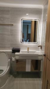 a bathroom with a sink and a toilet and a mirror at Romantic beach apartment芭堤雅水系高档酒店式公寓可做饭 in Jomtien Beach