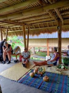 Un groupe de personnes assises au sol d'une cabane dans l'établissement Tetebatu Flush Harmony, à Tetebatu