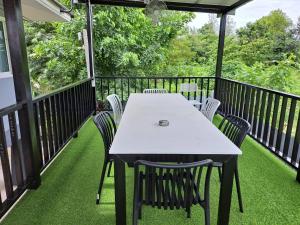 a table and chairs on a deck with grass at โคซี่ โฮมสเตย์ in Suan Phung