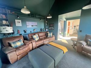 una sala de estar con un sofá de cuero marrón y sillas en Luxury Lake View House en Lake Tekapo