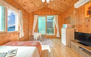 a bedroom with a bed and a television in a room at Sunbeach Pension in Geoje 