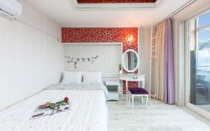 a bedroom with a bed and a table and a mirror at Sunbeach Pension in Geoje 