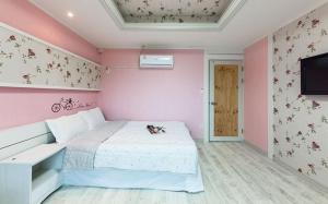 a bedroom with a white bed and a pink wall at Sunbeach Pension in Geoje 